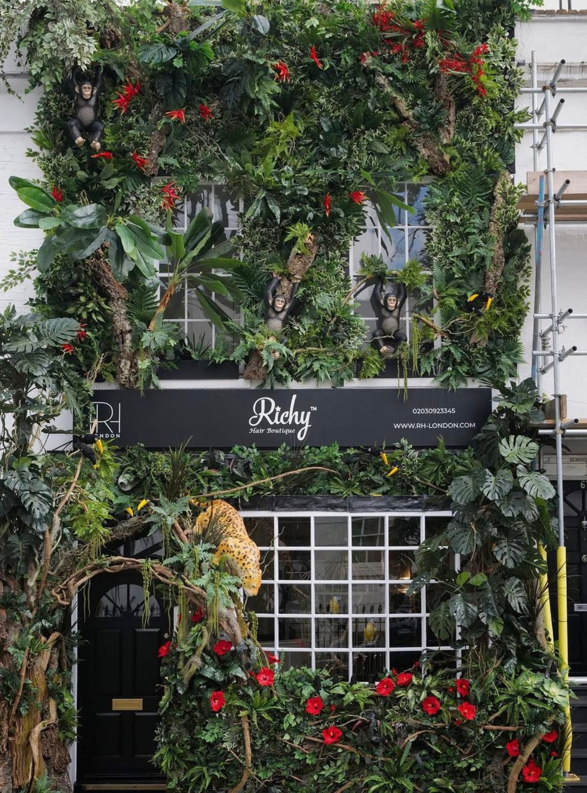 Large jungle style installation on a building reinstallation appears to be three stories high covered in lush thick jungle Foliage with monkeys, leopards and other jungle animals